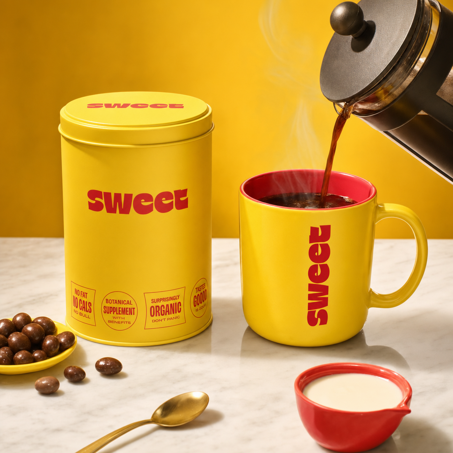 Yellow SWEET tin beside a matching SWEET mug on a marble counter as coffee is poured from a French press